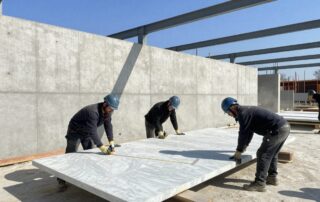 Maler messen mit Lasermessgerät an einer großen Marmorscheibe auf Baustelle in Deutschland
