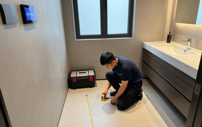 Techniker misst mit Lasermesser und Maßband in einem zeitgemäßen Badezimmer, während ein digitales Display die Abmessungen anzeigt