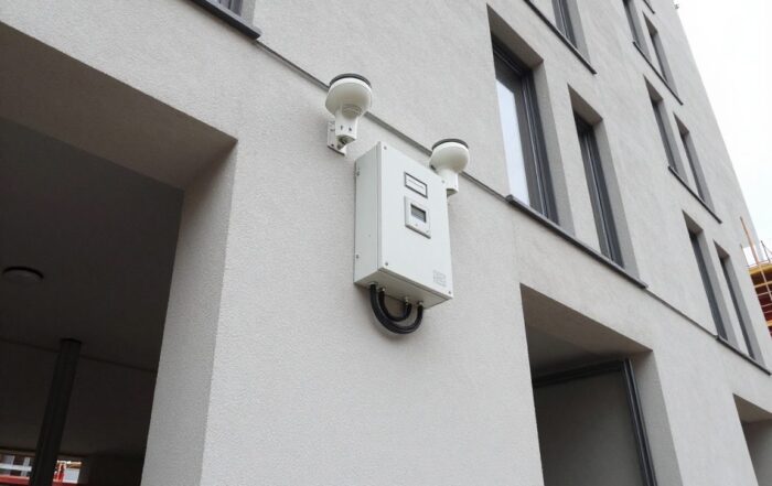 Neuer Alarmanlagen-Installationsbereich an einer deutschen Baustellenfassade mit Sensoren, Steuergerät und Verkabelung