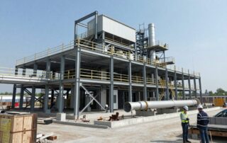 Weitwinkelaufnahme eines modernen deutschen Industrieanlagens bei Bau, Stahlrahmen, Betonfundament und großen Rohren, Arbeiter mit Helmen prüfen den Standort