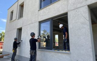 Arbeiter installieren Doppelverglasung an einer Wohnhausfassade auf einem modernen deutschen Baustellenplatz bei Tageslicht