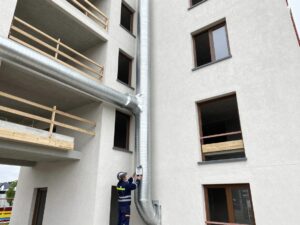 Techniker misst Temperaturen an moderner deutschen Wohngebäude mit sichtbarem HVAC-Rohrwerk