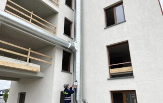 Techniker misst Temperaturen an moderner deutschen Wohngebäude mit sichtbarem HVAC-Rohrwerk