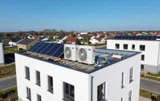 Wärmepumpen-Installation auf dem Dach eines modernen deutschen Wohngebäudes unter klarem Himmel, umgeben von Grünflächen
