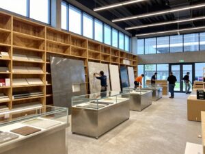 Weitwinkelaufnahme moderner Ladenbaufassade mit Holzregalen, Edelstahlarmaturen, Glasvitrinen und natürlichem Licht auf Baustelle in Deutschland