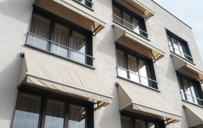 Weitwinkelaufnahme eines modernen deutschen Wohnhauses mit ausfahrbaren Markisen an den Fenstern, sichtbare Stoffstruktur und Metallrahmen im Sonnenlicht