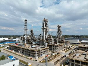 Modernes deutsches Industriekomplex mit Hochhäusern, Blitzableitern und Erdungssystemen; Arbeiter in Sicherheitswesten prüfen die Installationen bei klarem Himmel