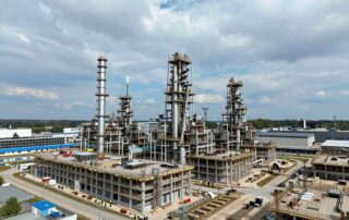 Modernes deutsches Industriekomplex mit Hochhäusern, Blitzableitern und Erdungssystemen; Arbeiter in Sicherheitswesten prüfen die Installationen bei klarem Himmel