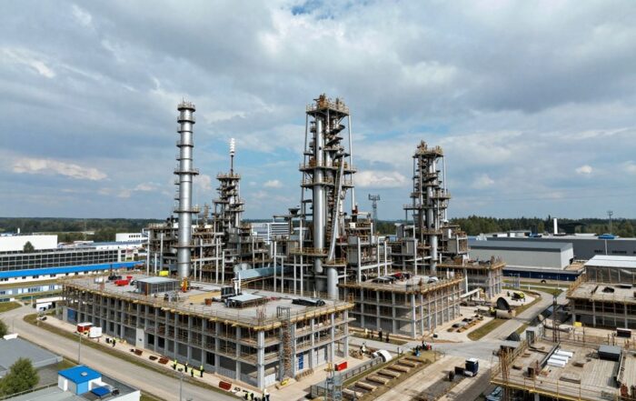 Modernes deutsches Industriekomplex mit Hochhäusern, Blitzableitern und Erdungssystemen; Arbeiter in Sicherheitswesten prüfen die Installationen bei klarem Himmel