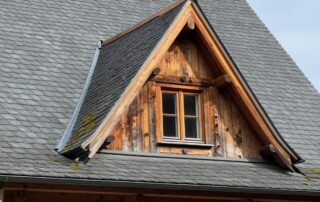 Fotorealistisches Bild eines deutschen Bauernhauses mit markantem Giebel und einer Gaube, Holzschindeln, Schieferziegel und Moos an den Sparren