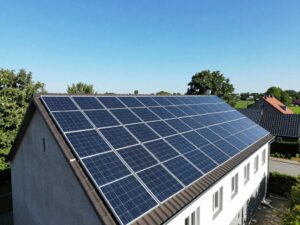 Weitwinkelaufnahme eines deutschen Ländereihofs mit Solarpanelen auf dem Dach, umgeben von Bäumen und Gebäuden, die leichte Schatten werfen