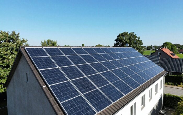 Weitwinkelaufnahme eines deutschen Ländereihofs mit Solarpanelen auf dem Dach, umgeben von Bäumen und Gebäuden, die leichte Schatten werfen