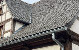 Metallhalter für Dachrinne auf dem Satteldach eines traditionellen deutschen Fachwerkhauses, sichtbar im Sonnenlicht