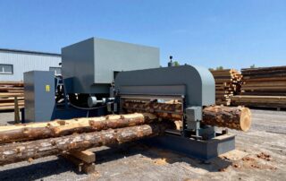 Weitwinkelaufnahme eines modernen deutschen Sägewerks mit großen industriellen Sägen, die Holzstämme schneiden, umgeben von Holzhaufen und Maschinen