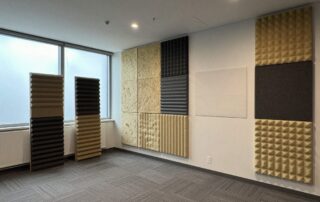 Weitwinkelaufnahme eines modernen Büros mit akustischen Paneelen an Wänden und Decke, Teppichboden und Tageslicht durch große Fenster