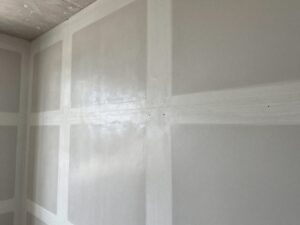 Nahaufnahme einer deutschen Baustelle mit Trockenbauwand, sauber gefüllten Fugen und abgedeckten Schraubenköpfen, glatt polierter Beton