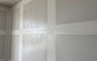 Nahaufnahme einer deutschen Baustelle mit Trockenbauwand, sauber gefüllten Fugen und abgedeckten Schraubenköpfen, glatt polierter Beton