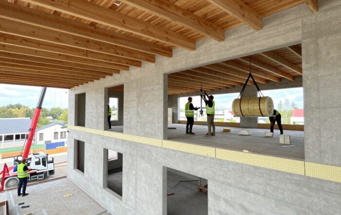 Modernes deutsches Wohnhaus im Bau: sichtbare Deckenbalken, Bodenplatten und installierte Dämmplatten aus Rigid-Foam und Mineralwolle