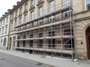 Großes professionelles Metallgerüst vor einem klassischen deutschen Stadtgebäude auf dem Gehweg.