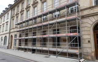 Großes professionelles Metallgerüst vor einem klassischen deutschen Stadtgebäude auf dem Gehweg.