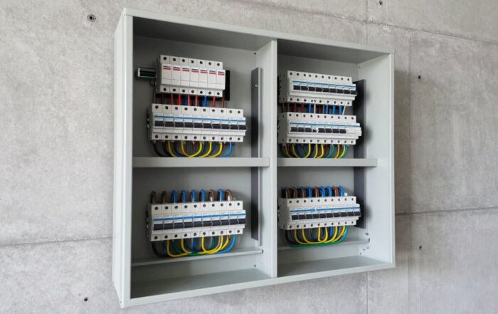 Geöffnete elektrische Unterverteilung mit ordentlich verlegten Leitungssperren und Sicherungsautomaten an einer Betonwand.